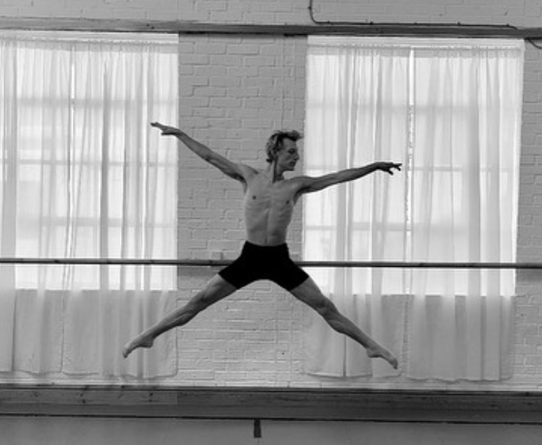 Sam performing a leap in a dance studio