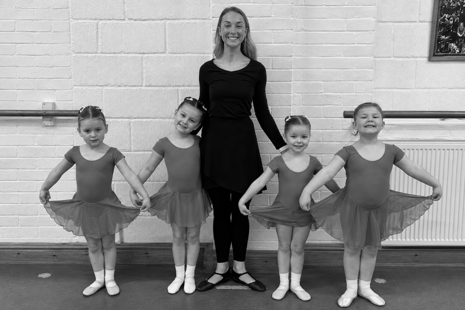 An LHTS ballet teacher with four smiling young dancers in class